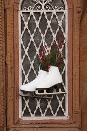 Photo of Pair of ice skates with Christmas decor hanging on old door