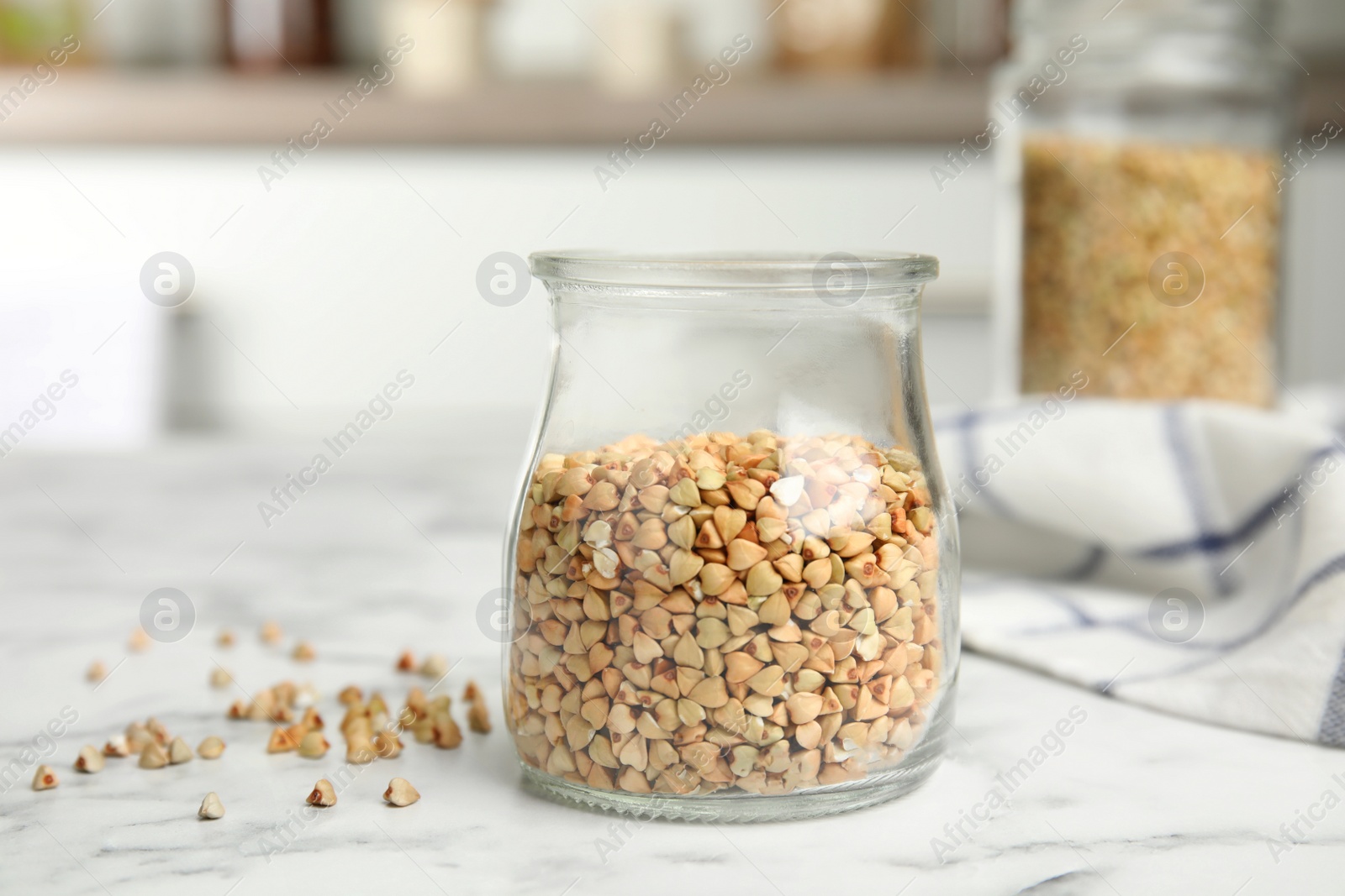 Photo of Uncooked green buckwheat grains on white marble table