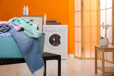 Photo of Laundry basket filled with clothes on bench in bathroom, closeup. Space for text
