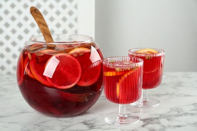 Photo of Glasses and bowl with aromatic punch drink on white marble table