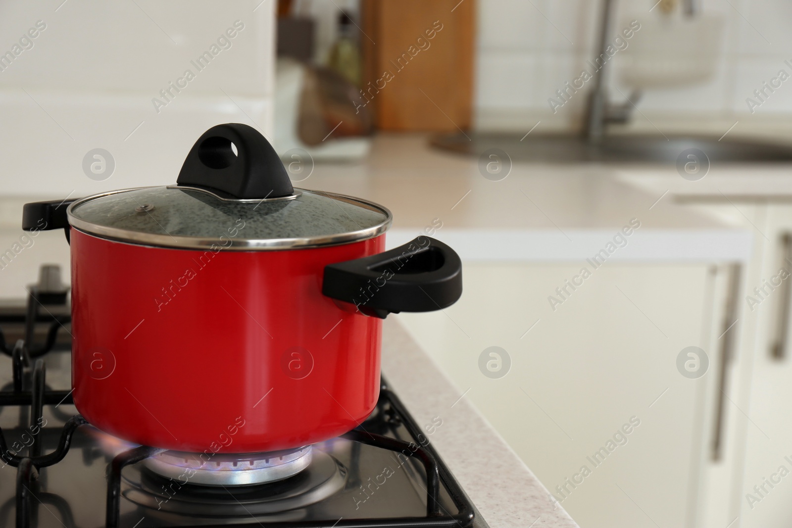 Photo of Red pot on modern kitchen stove with burning gas. Space for text