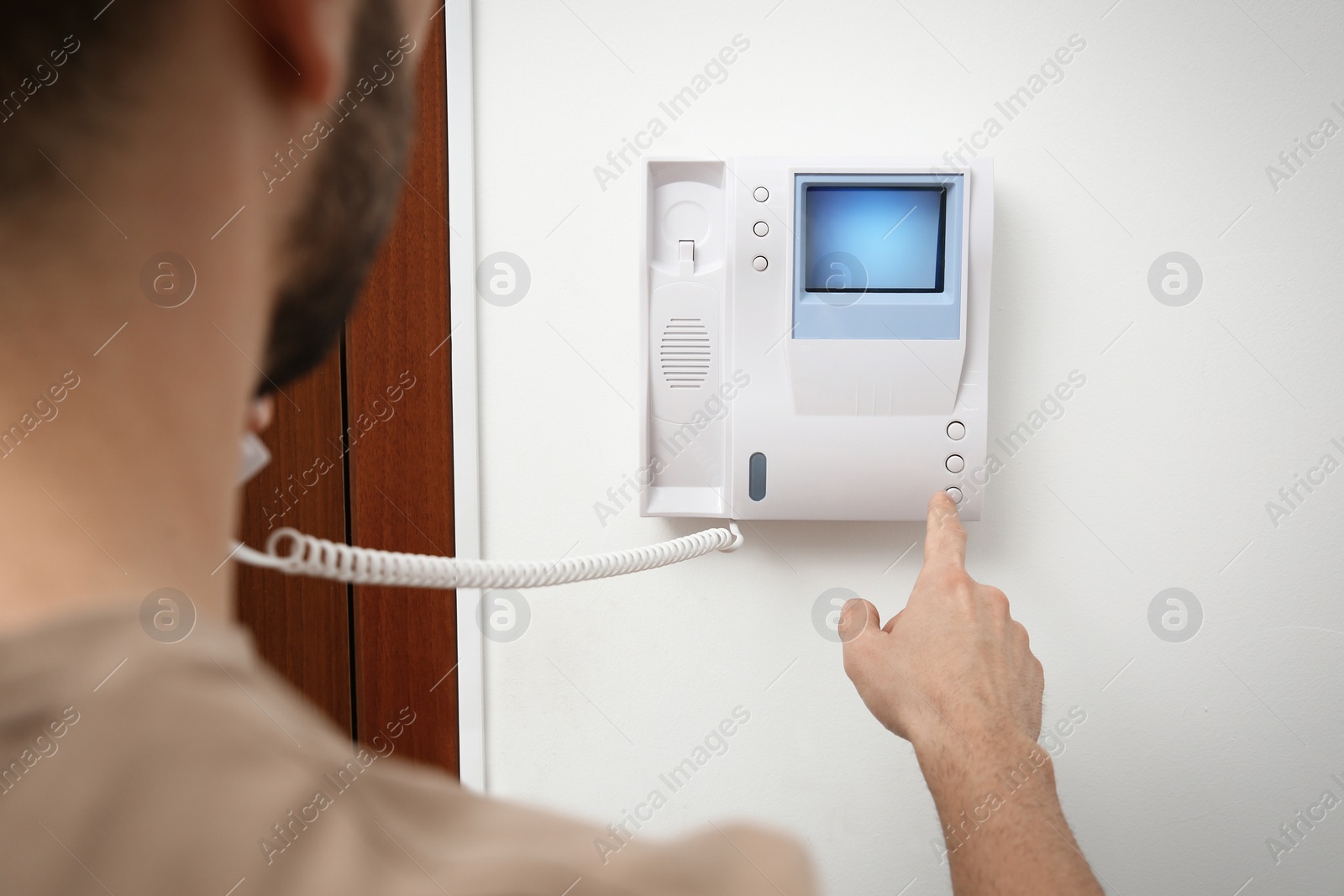 Photo of Man pressing button on intercom panel indoors, closeup