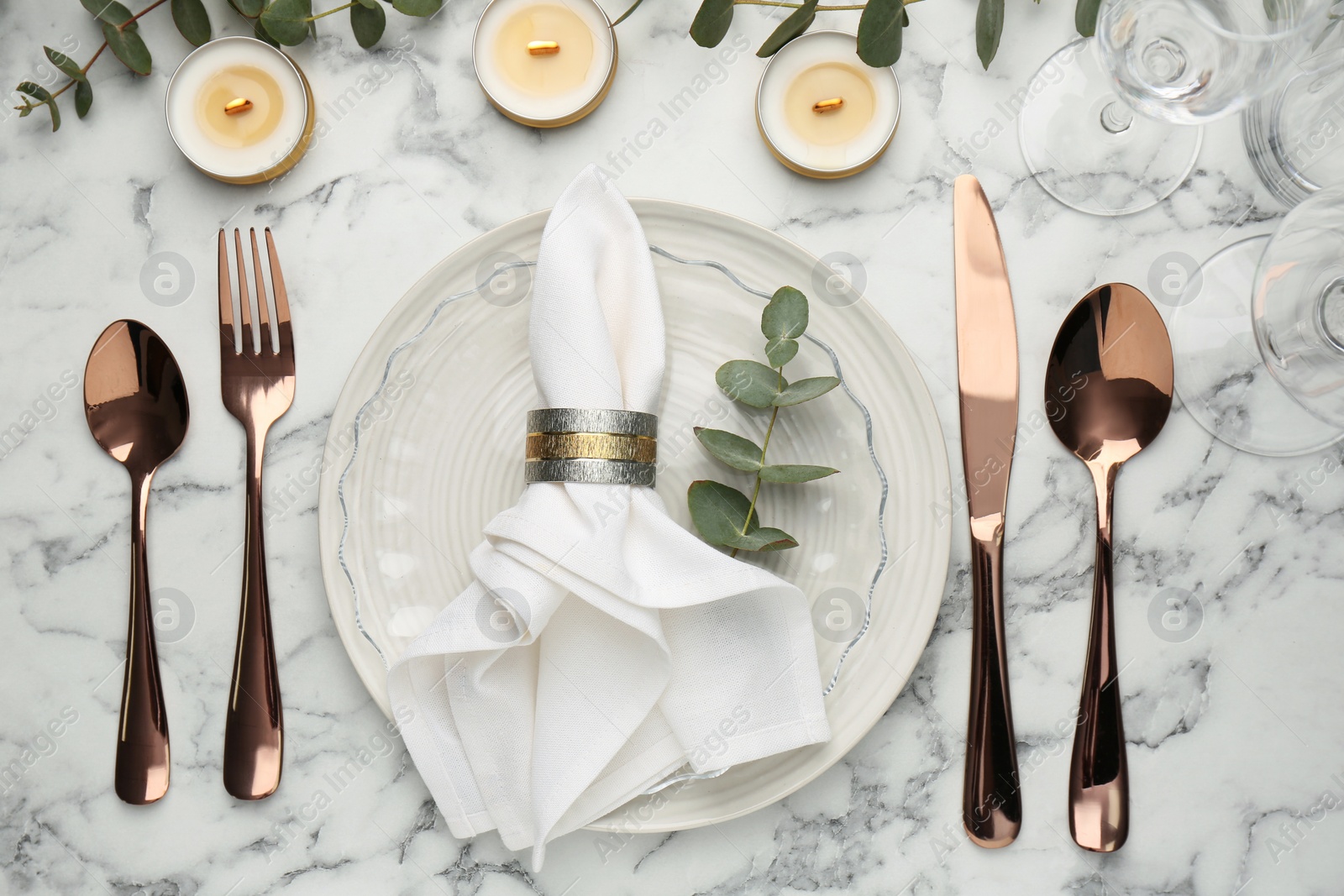 Photo of Beautiful place setting with candles and eucalyptus on white marble table, flat lay