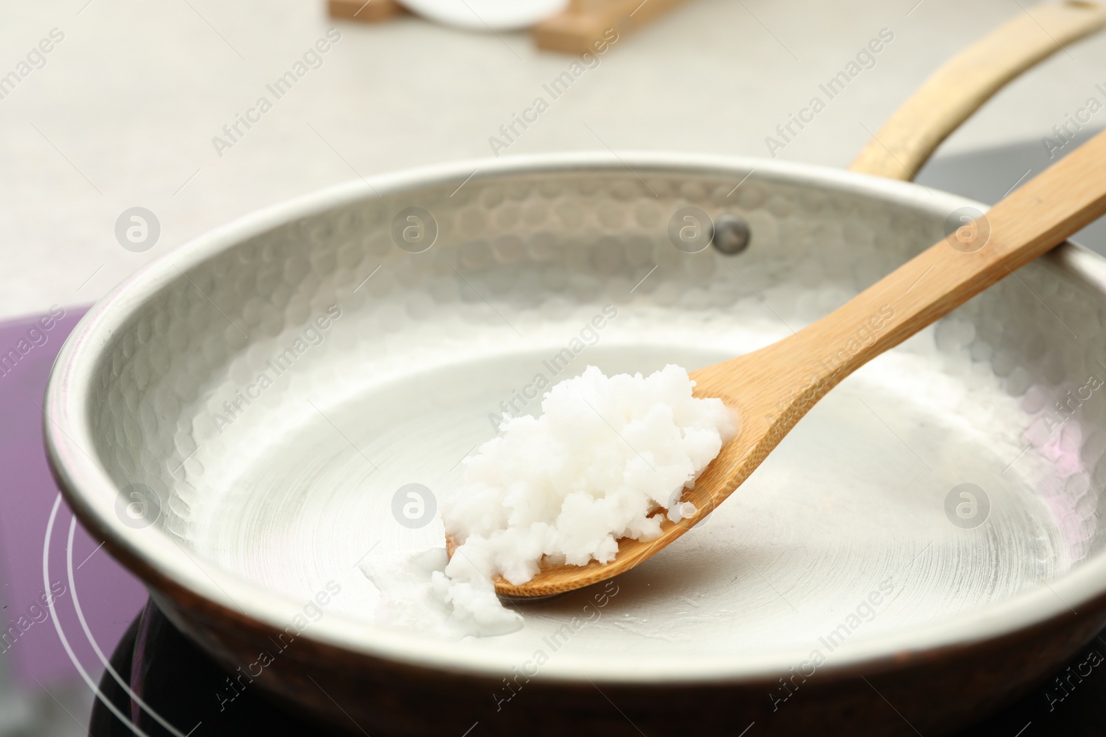 Photo of Frying pan with coconut oil on induction stove, closeup. Healthy cooking