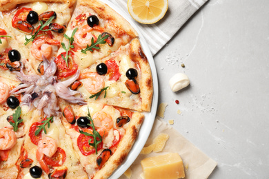Tasty pizza with seafood and ingredients on light grey marble table, flat lay