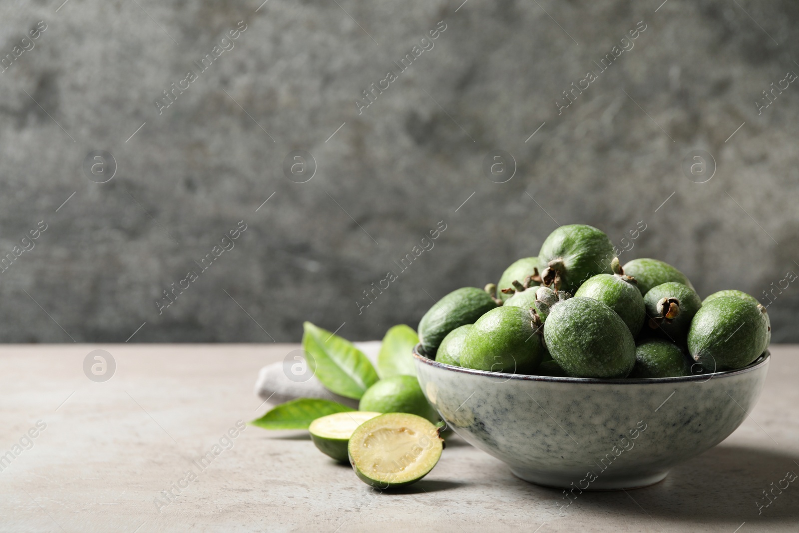 Photo of Fresh green feijoa fruits on light grey table, space for text