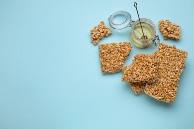 Puffed rice bars (kozinaki) and honey on light blue background, above view. Space for text