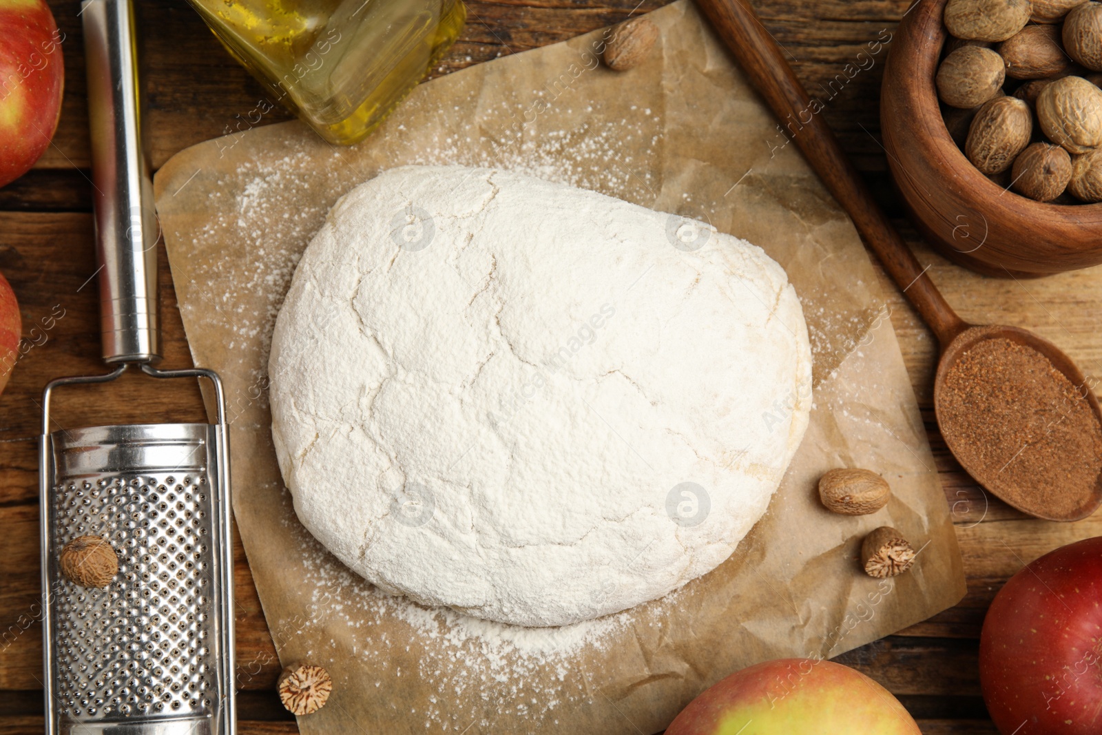 Photo of Raw dough, nutmeg seeds and other ingredients for pastry on wooden table, flat lay