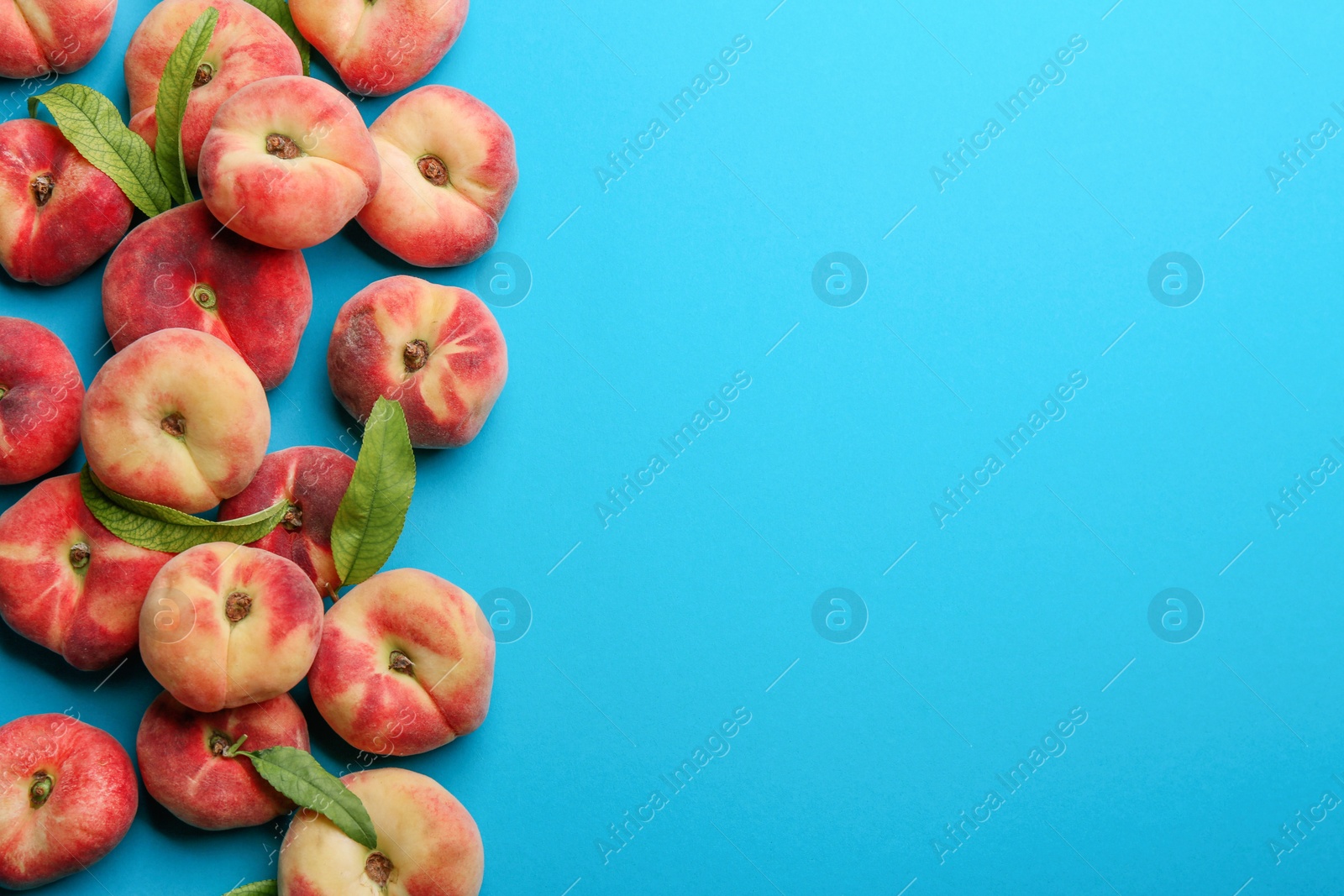 Photo of Fresh donut peaches on blue background, flat lay. Space for text