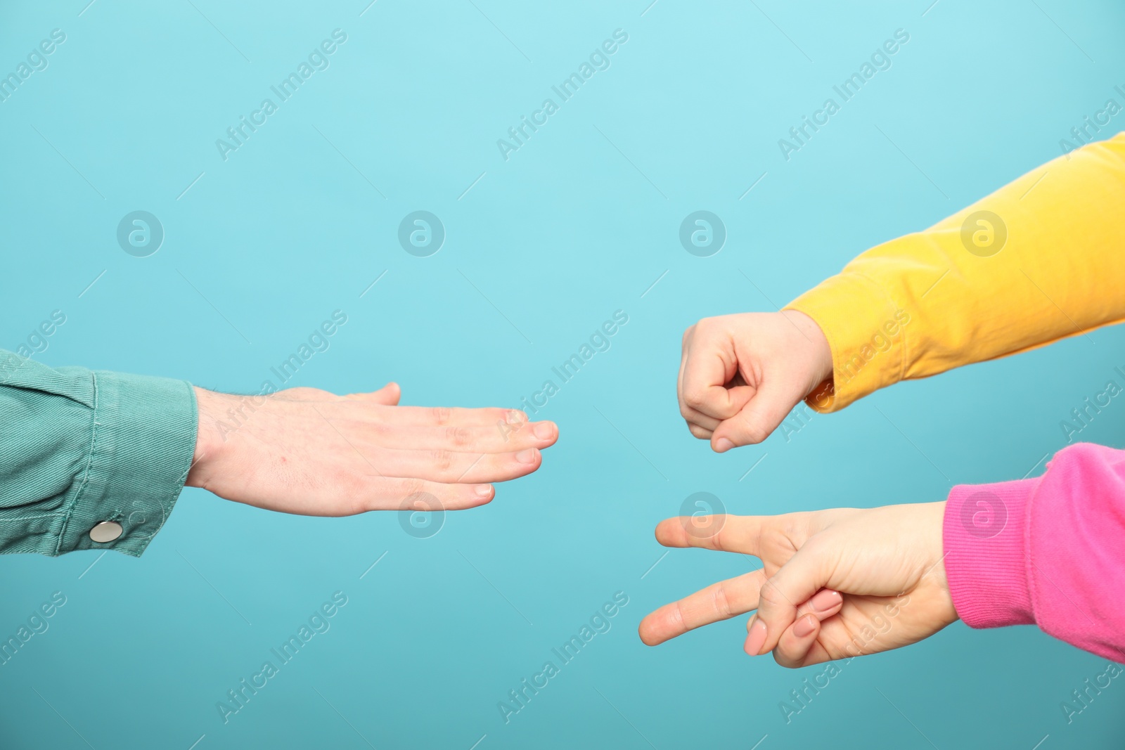 Photo of People playing rock, paper and scissors on light blue background, closeup