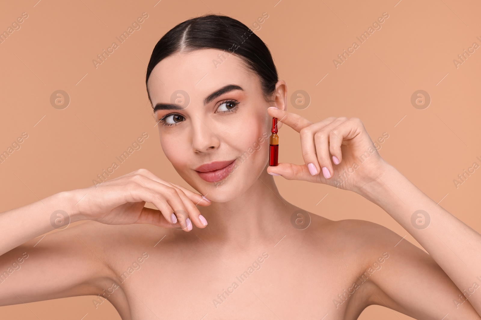 Photo of Beautiful young woman holding skincare ampoule on beige background