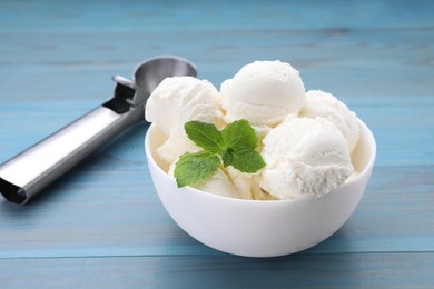 Photo of Delicious vanilla ice cream, mint and scoop on light blue wooden table