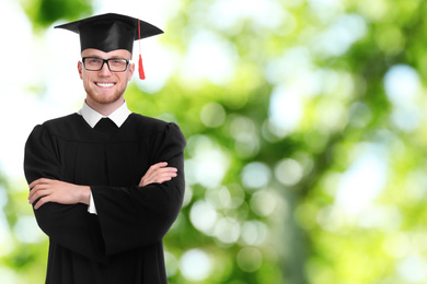 Image of Happy student wearing graduation hat on blurred background, space for text