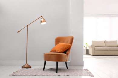 Image of Comfortable orange armchair with cushion in stylish room interior