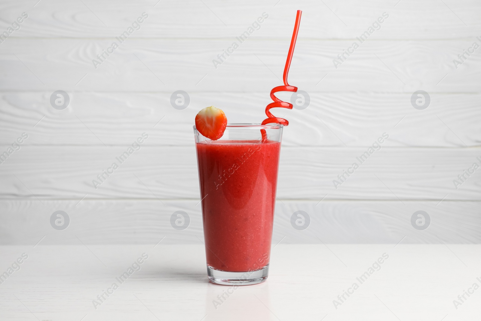 Photo of Glass with delicious strawberry smoothie on white wooden table