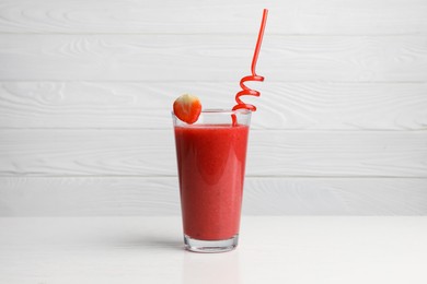 Photo of Glass with delicious strawberry smoothie on white wooden table