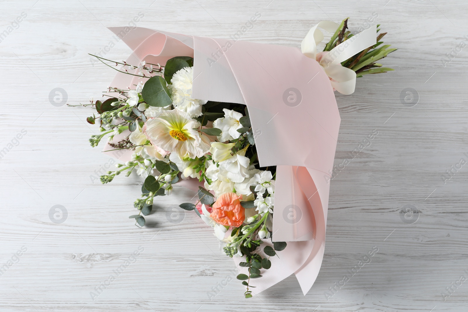 Photo of Bouquet of beautiful flowers on white wooden table, above view