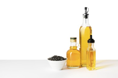 Bottles of different cooking oils and sunflower seeds on white background, space for text
