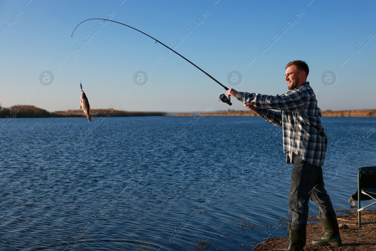 Photo of Fisherman catching fish with rod at riverside