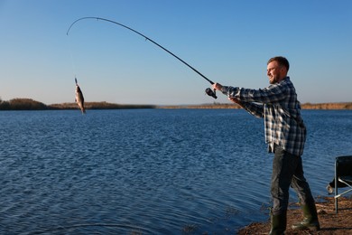 Photo of Fisherman catching fish with rod at riverside