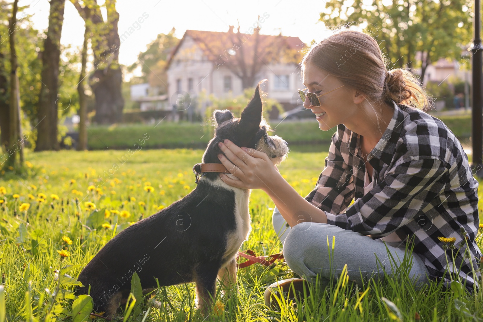 Photo of Teenage girl with her cute dog resting on green grass in park