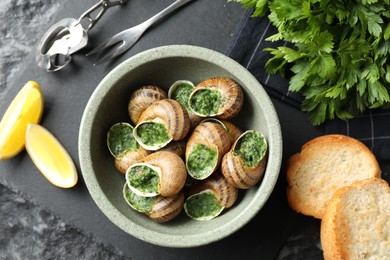 Delicious cooked snails served on grey textured table, flat lay