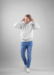 Full length portrait of man in hoodie sweater on light background. Space for design