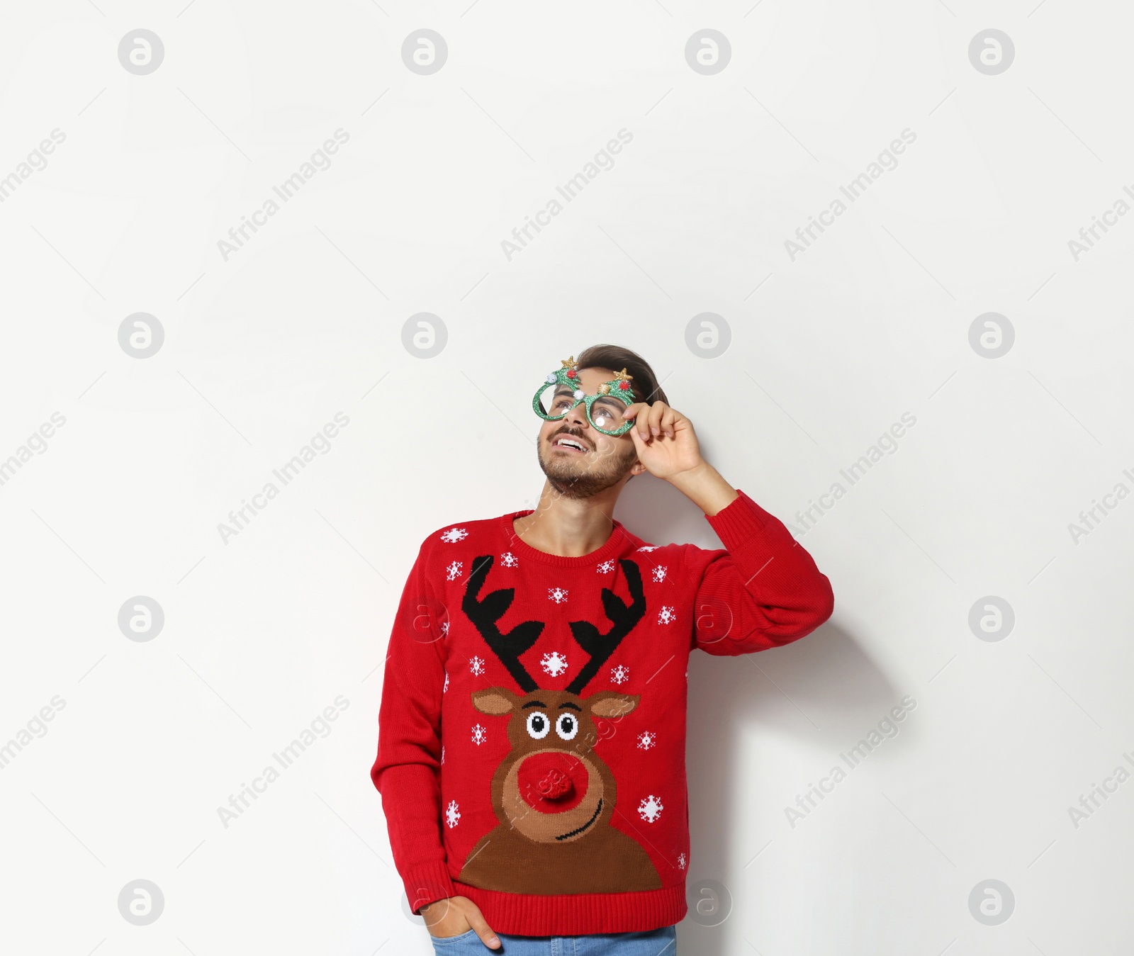 Photo of Young man in Christmas sweater with party glasses on white background