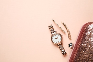 Photo of Luxury wrist watch, hairpins and clutch on pink background, flat lay. Space for text