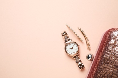 Luxury wrist watch, hairpins and clutch on pink background, flat lay. Space for text