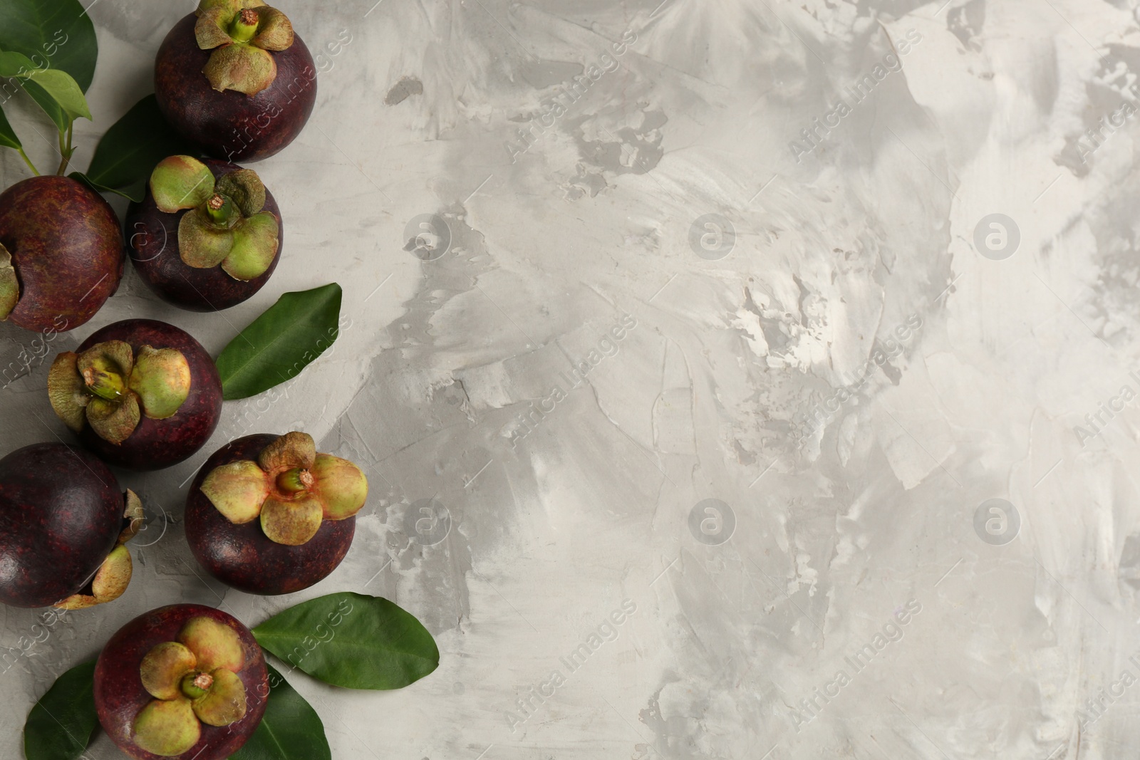 Photo of Fresh ripe mangosteen fruits on light grey table, flat lay. Space for text