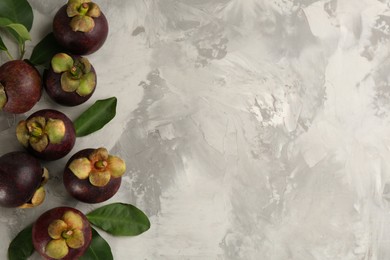 Photo of Fresh ripe mangosteen fruits on light grey table, flat lay. Space for text