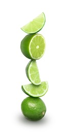 Image of Stacked whole and cut limes on white background