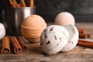 Bath bombs with cinnamon sticks on wooden table