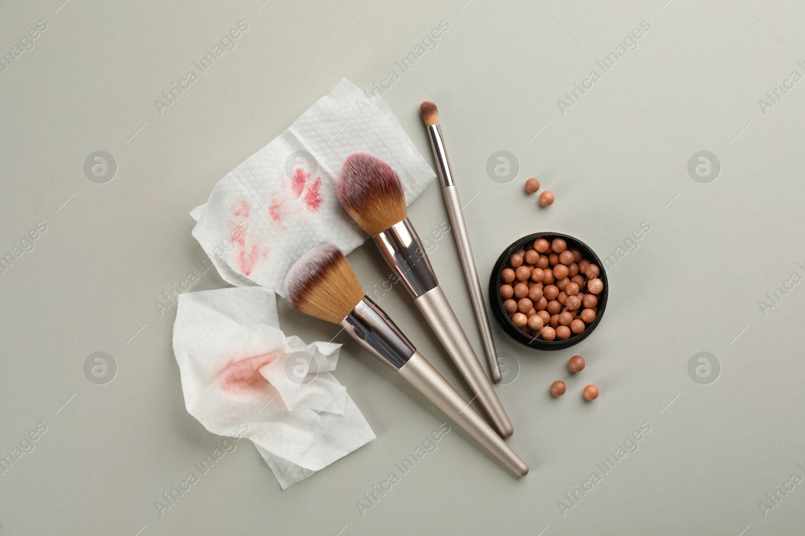 Photo of Dirty wet wipes with brushes and cosmetic on light background, flat lay