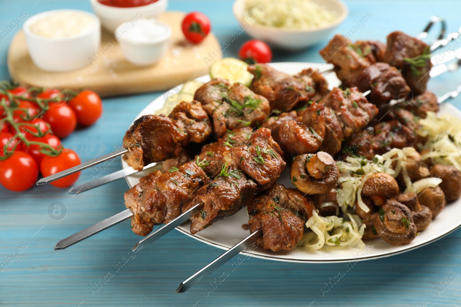 Photo of Metal skewers with delicious meat and vegetables served on light blue wooden table, closeup