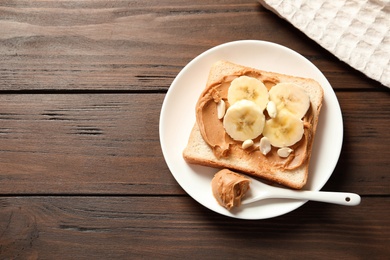 Toast bread with peanut butter and banana slices on wooden table