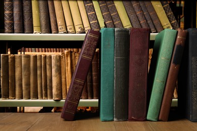 Many hardcover books on wooden table in library, space for text