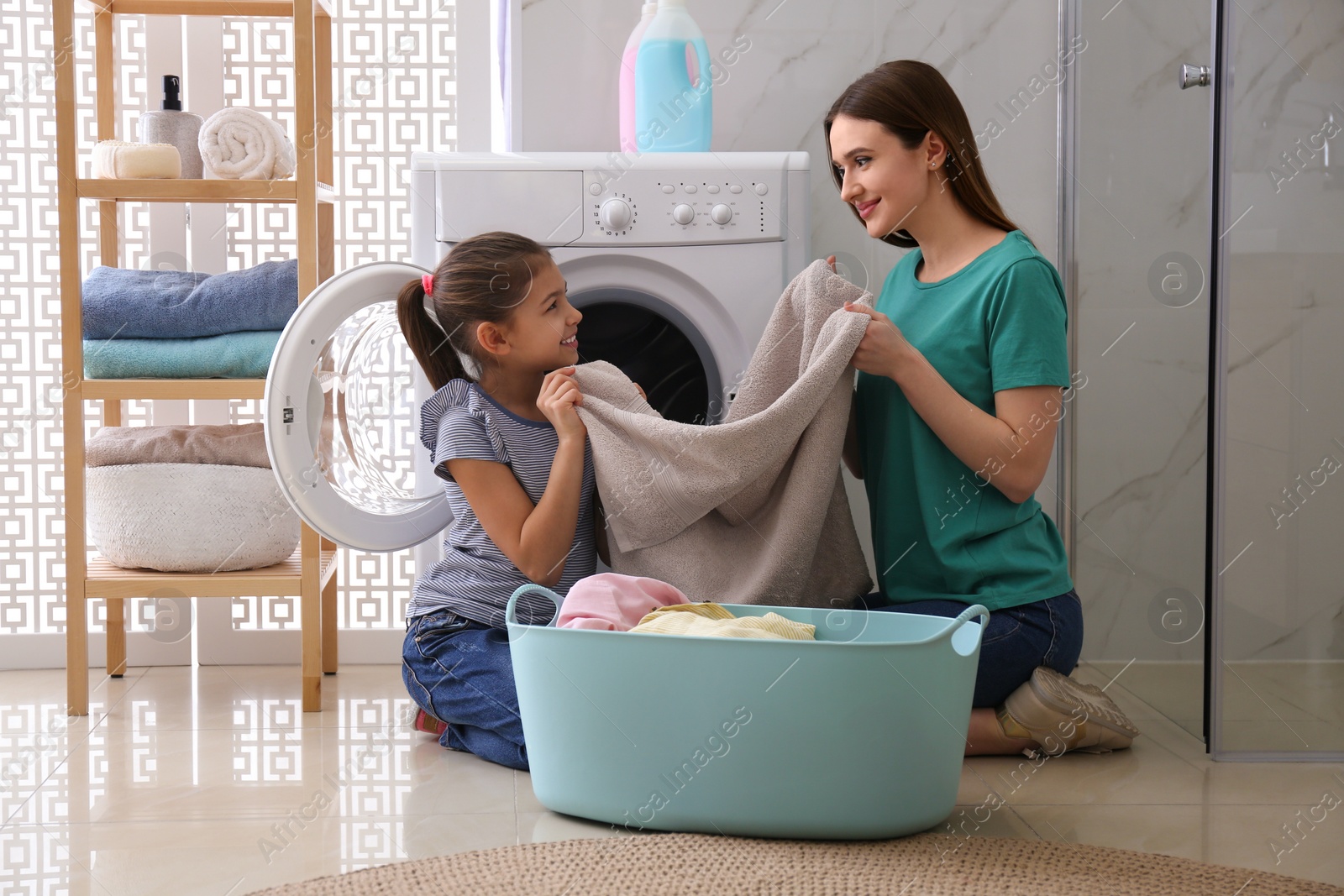 Photo of Mother and little daughter with clean laundry in bathroom