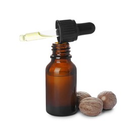 Photo of Bottle of nutmeg oil, pipette and nuts on white background