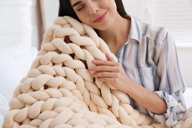 Photo of Young woman with chunky knit blanket at home, closeup