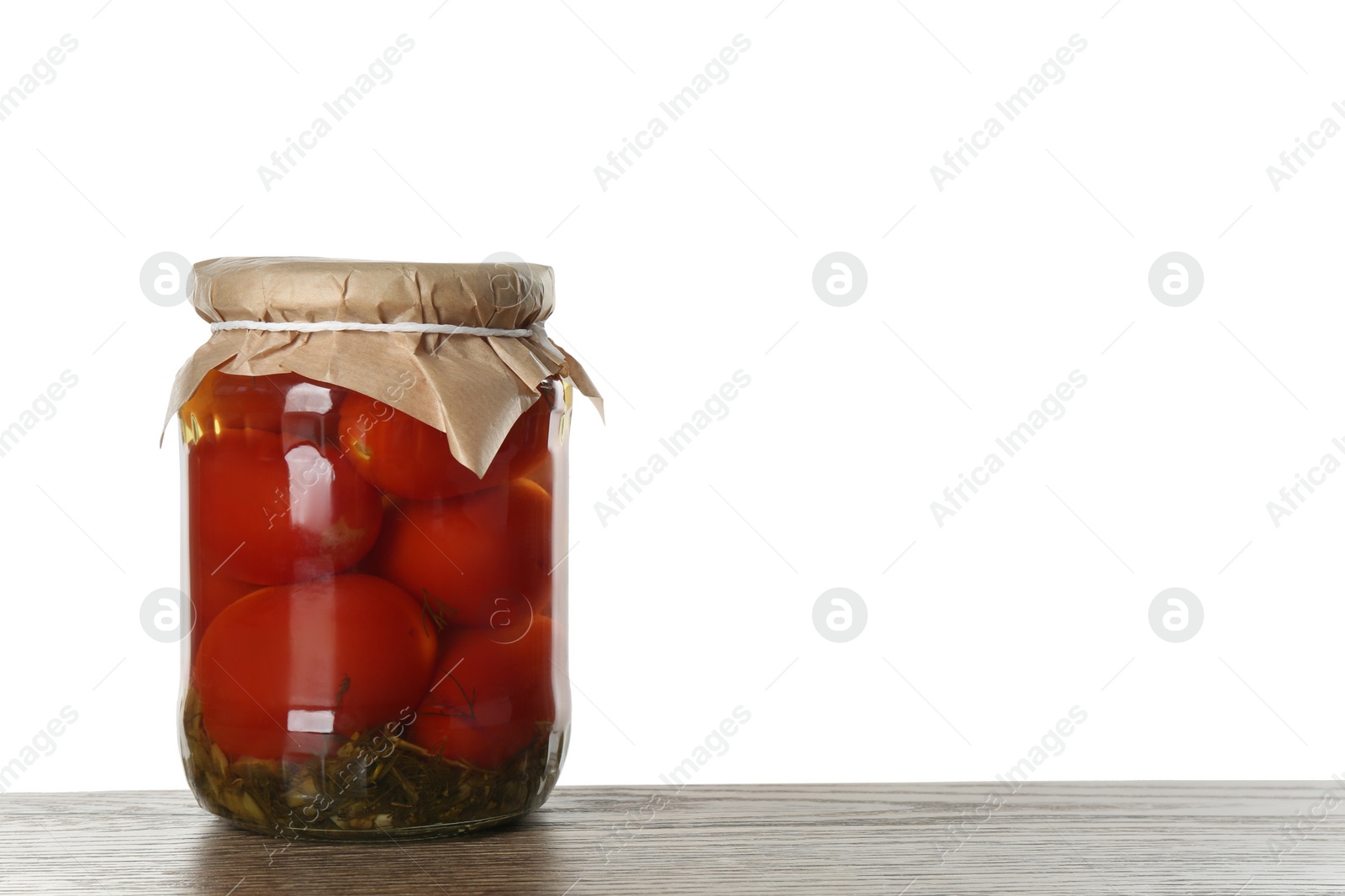 Photo of Glass jar of pickled tomatoes on wooden table against white background. Space for text