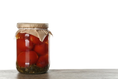 Photo of Glass jar of pickled tomatoes on wooden table against white background. Space for text