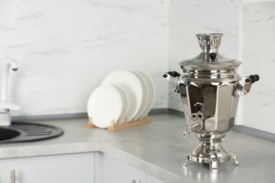 Photo of Metal samovar on grey countertop in kitchen. Russian tea culture