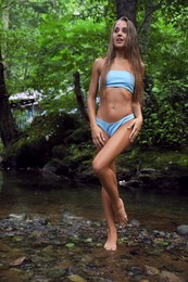 Photo of Beautiful young woman in light blue bikini near mountain river outdoors