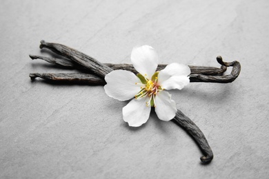 Photo of Aromatic vanilla sticks and flower on grey background