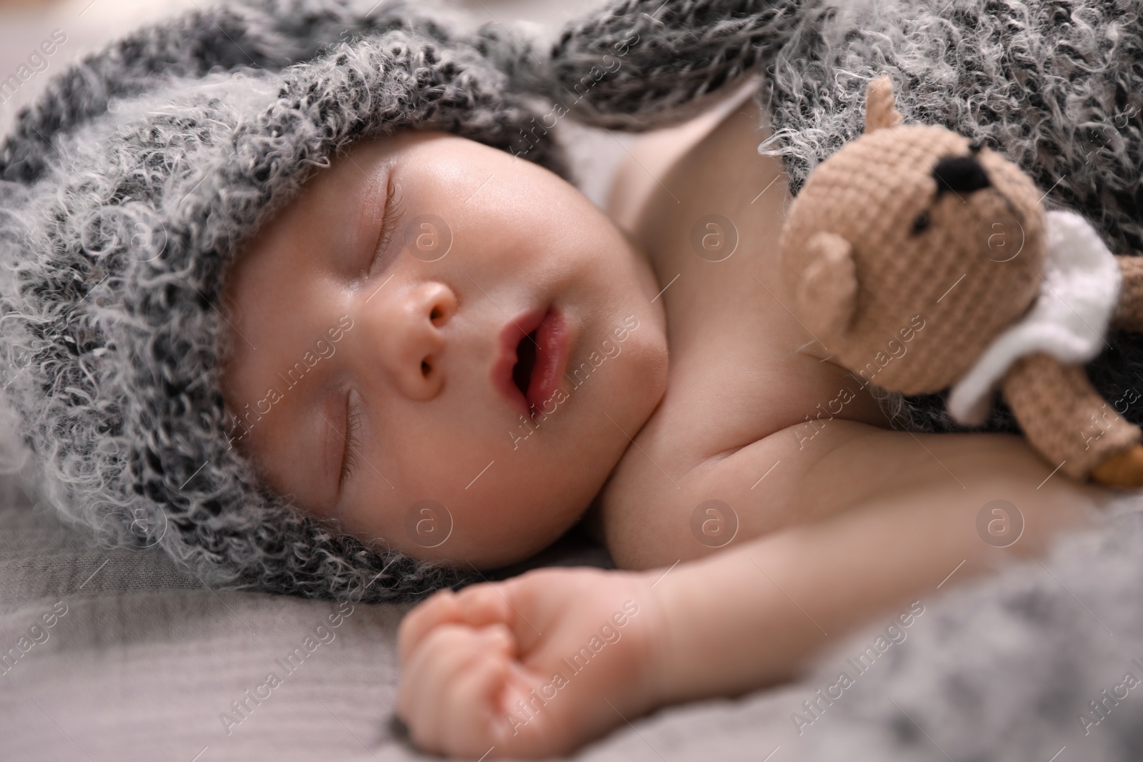 Photo of Cute newborn baby sleeping with teething toy in bed, closeup