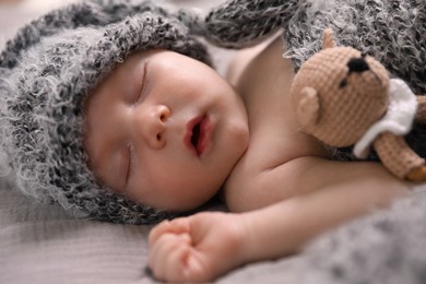 Cute newborn baby sleeping with teething toy in bed, closeup