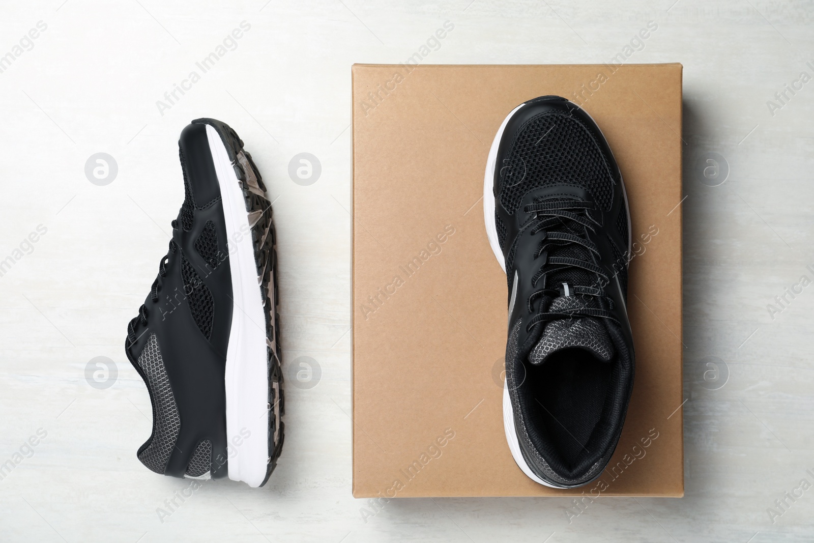 Photo of Pair of stylish sneakers and box on white wooden background, flat lay