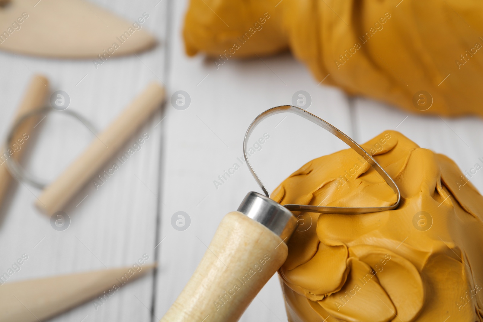 Photo of Clay with loop tool near other modeling instruments on white table, closeup